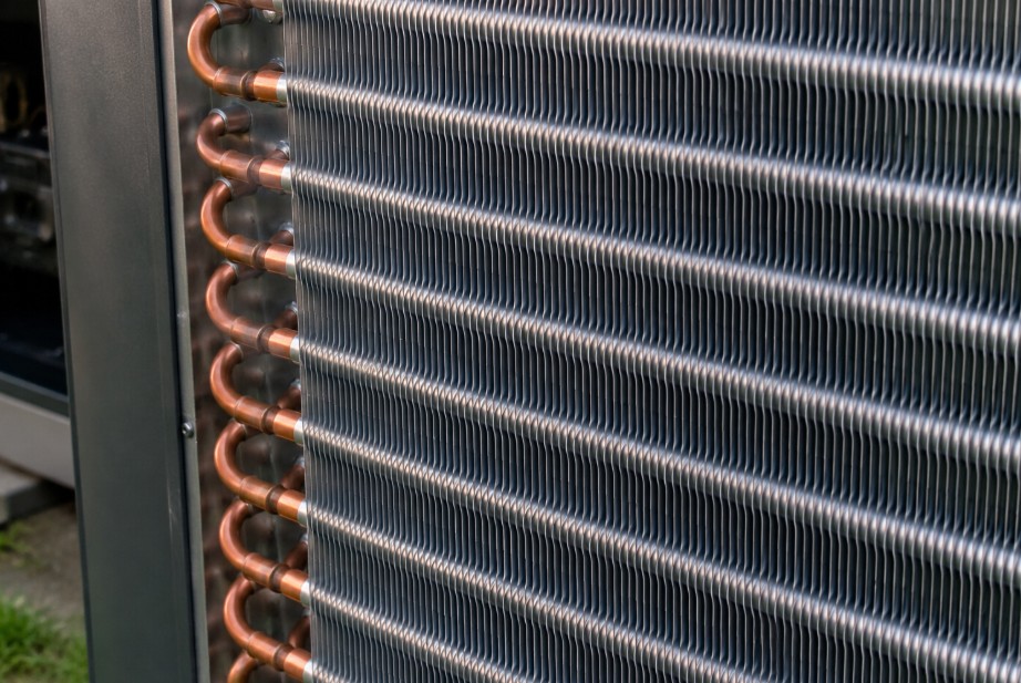 Close-up of aluminum condenser coil fins on a residential HVAC outdoor unit showing clean and evenly spaced metal fins with copper refrigerant tubing running through the assembly